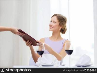 reastaurant and happiness concept - smiling young woman giving menu to waiter at restaurant