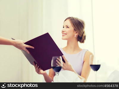reastaurant and happiness concept - smiling young woman recieving menu from waiter at restaurant. smiling woman recieving menu from waiter