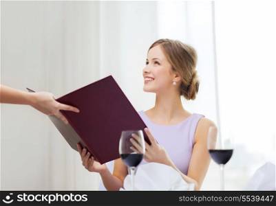 reastaurant and happiness concept - smiling young woman recieving menu from waiter at restaurant