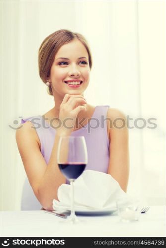 reastaurant and happiness concept - smiling young woman with glass of red whine waiting for date at restaurant. smiling woman with glass of whine waiting for date