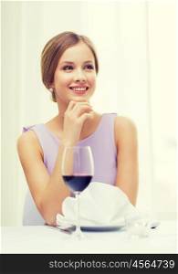 reastaurant and happiness concept - smiling young woman with glass of red whine waiting for date at restaurant. smiling woman with glass of whine waiting for date