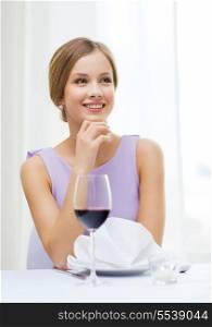 reastaurant and happiness concept - smiling young woman with glass of red whine waiting for date at restaurant