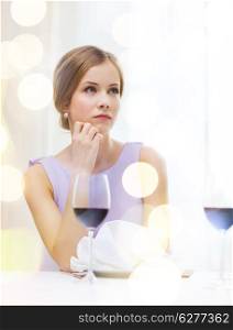 reastaurant and happiness concept - upset young woman with glass of red whine waiting for date at restaurant