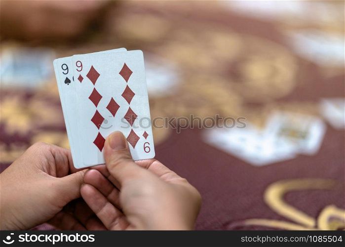 Reaw view closeup of asian woman playing card with money on the table over the carpet, risk and luck game concept