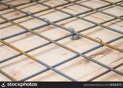 Rebars steel wire mesh, which is supported by mortar cover box and wooden plate for precast concrete flooring on construction site, selective focus.