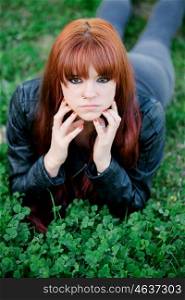 Rebellious teenager girl with red hair lying on the grass