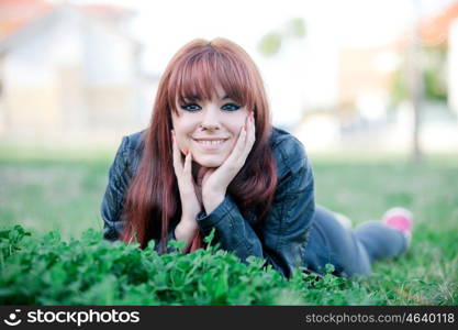 Rebellious teenager girl with red hair lying on the grass