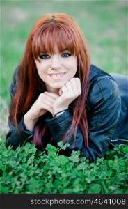 Rebellious teenager girl with red hair lying on the grass