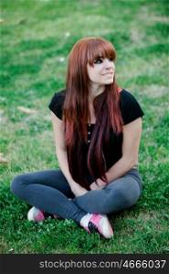 Rebellious teenager girl with red hair sitting on the grass