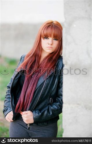 Rebellious teenager girl with red hair very angry leaning on a wall