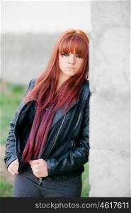 Rebellious teenager girl with red hair very angry leaning on a wall