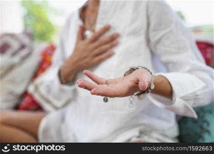 Receiving Energy Hand Gesture. Woman sitting in a lotus position with left palm raised upward to receive positive energy. . Receiving Positive Energy, Practitioner Meditating on Receiving Ability