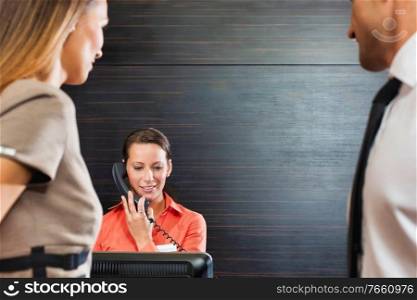 Receptionist calling for assistance while business people waiting in lobby