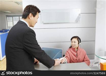 Receptionist giving a businessman a bill