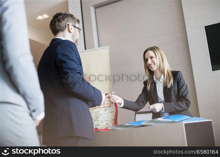 Receptionist giving identity card to businessman at convention center