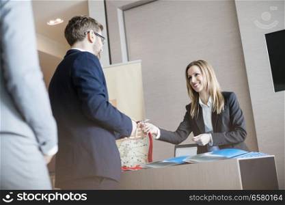 Receptionist giving identity card to businessman at convention center