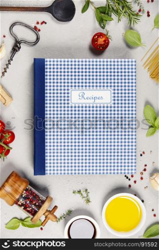 Recipe book, Olive oil, balsamic vinegar, salt, pepper, herbs, pasta, tomatoes on concrete background - cooking ingredients background -- top view - space for text. Healthy food, vegetarian or italian food concept.