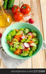 Recipe for vegetable salad with tomatoes, cucumbers and radishes. Seasonal dish on a wooden background. Vegan food for diet.. Recipe for vegetable salad with tomatoes, cucumbers and radishes. Seasonal dish on wooden background. Vegan food for diet.