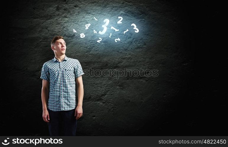 Reckoning man. Young man and looking at numerals against dark background