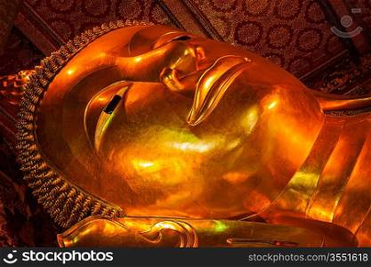Reclining Buddha gold statue face close up. Wat Pho, Bangkok, Thailand