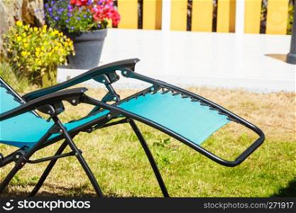 Recreation and relaxation objects concept. Blue modern sunbed deck chair in garden.. Blue sunbed deck chair in garden