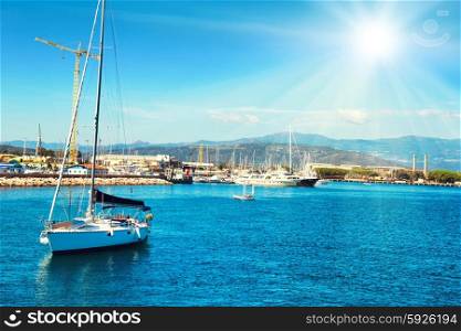 Recreation sail boat with people near the shore. Blue sea and bright sun on the background