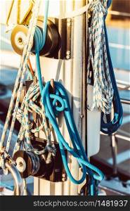 Recreational yacht detail with ropes and other equipment. Filtered shot with sun reflection in background