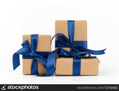 rectangle box wrapped in brown kraft paper and tied with a silk blue ribbon, gift isolated on a white background