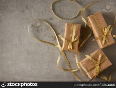rectangular box wrapped in brown paper and tied with a silk ribbon with a bow, gift on a gray background, top view, copy space