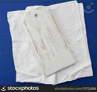 rectangular empty white kitchen cutting board and white textile towel on a blue wooden background from boards, top view