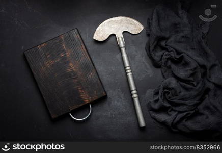 Rectangular empty wooden cutting board and kitchen knife on black table with gauze napkin, top view