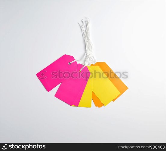 rectangular paper pinks, yellow and orange tags for things on a white rope, white background