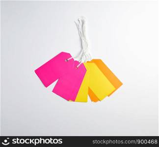 rectangular paper pinks, yellow and orange tags for things on a white rope, white background