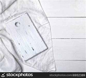 rectangular white cutting board on white textile tablecloth, top view, empty space on the right
