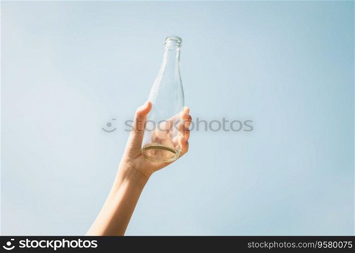 Recyclable glass bottle held in hand up on sky background. Hand holding plastic waste for recycle reduce and reuse concept to promote clean environment with effective recycling management. Gyre. Recyclable glass waste held in hand up on sky background. Gyre