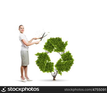 Recycle concept. Young attractive businesswoman cutting plant in shape of recycle symbol