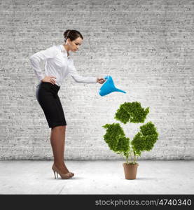 Recycle concept. Young attractive businesswoman watering plant in pot with can