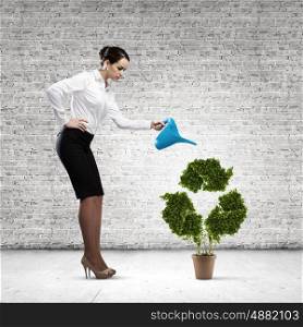 Recycle concept. Young attractive businesswoman watering plant in pot with can