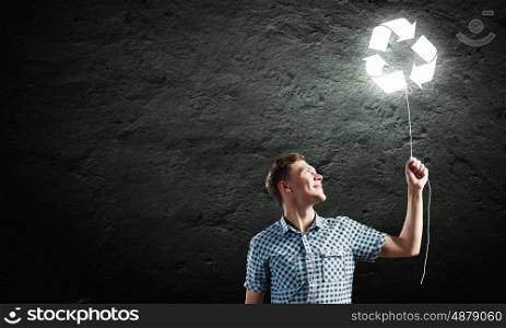 Recycle concept. Young handsome man with recycle balloon against dark backdrop