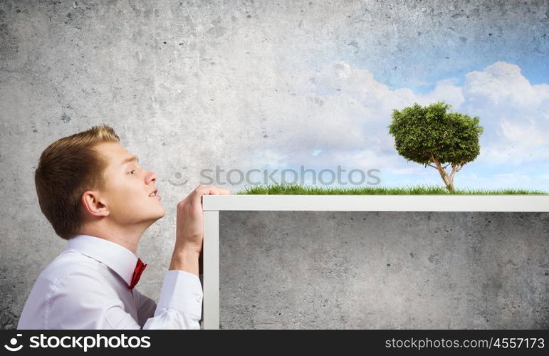 Recycle concept. Young man in glasses and pot with recycle sign on table