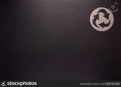 Recycle symbol at black paper as background texture. Recycling concept and paper