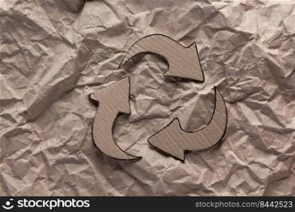 Recycle symbol at  crumpled paper background texture. Recycling idea concept and cardboard paper
