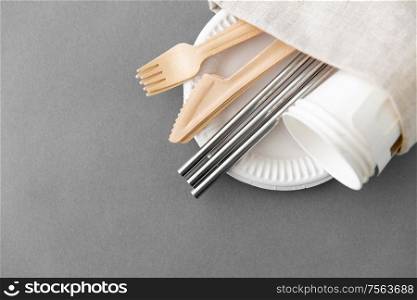 recycling and eco friendly concept - set of wooden forks, knives, paper cups and metallic straws with napkin on plate on grey background. wooden forks, knives and paper cups on plate