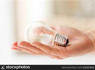 recycling, electricity, environment and ecology concept - close up of hand holding lightbulb or incandescent lamp