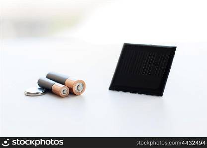 recycling, energy, power, environment and ecology concept - close up of alkaline batteries and solar cell