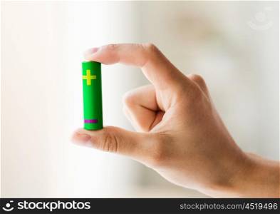 recycling, energy, power, environment and ecology concept - close up of hand holding green alkaline battery