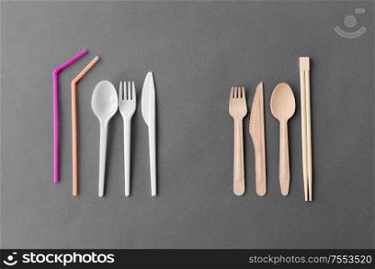 recycling, environment and eco friendly concept - close up of natural wooden spoon, knive, fork and chopsticks and plastic dishes on table. close up of eco friendly and plastic tableware