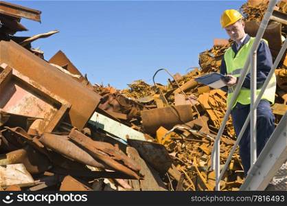 Recycling expert, standing on a metal staircase in front of a steel scrap heap