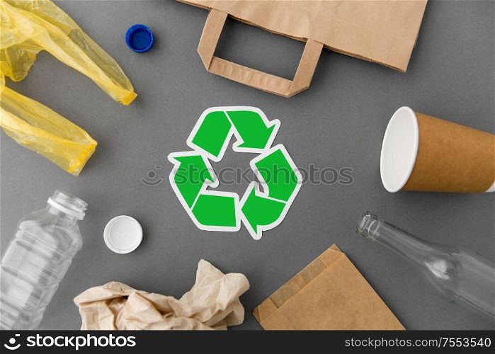 recycling, garbage disposal and ecology concept - green recycle symbol with household waste on grey background. green recycle symbol with household waste on grey