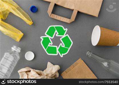 recycling, garbage disposal and ecology concept - green recycle symbol with household waste on grey background. green recycle symbol with household waste on grey